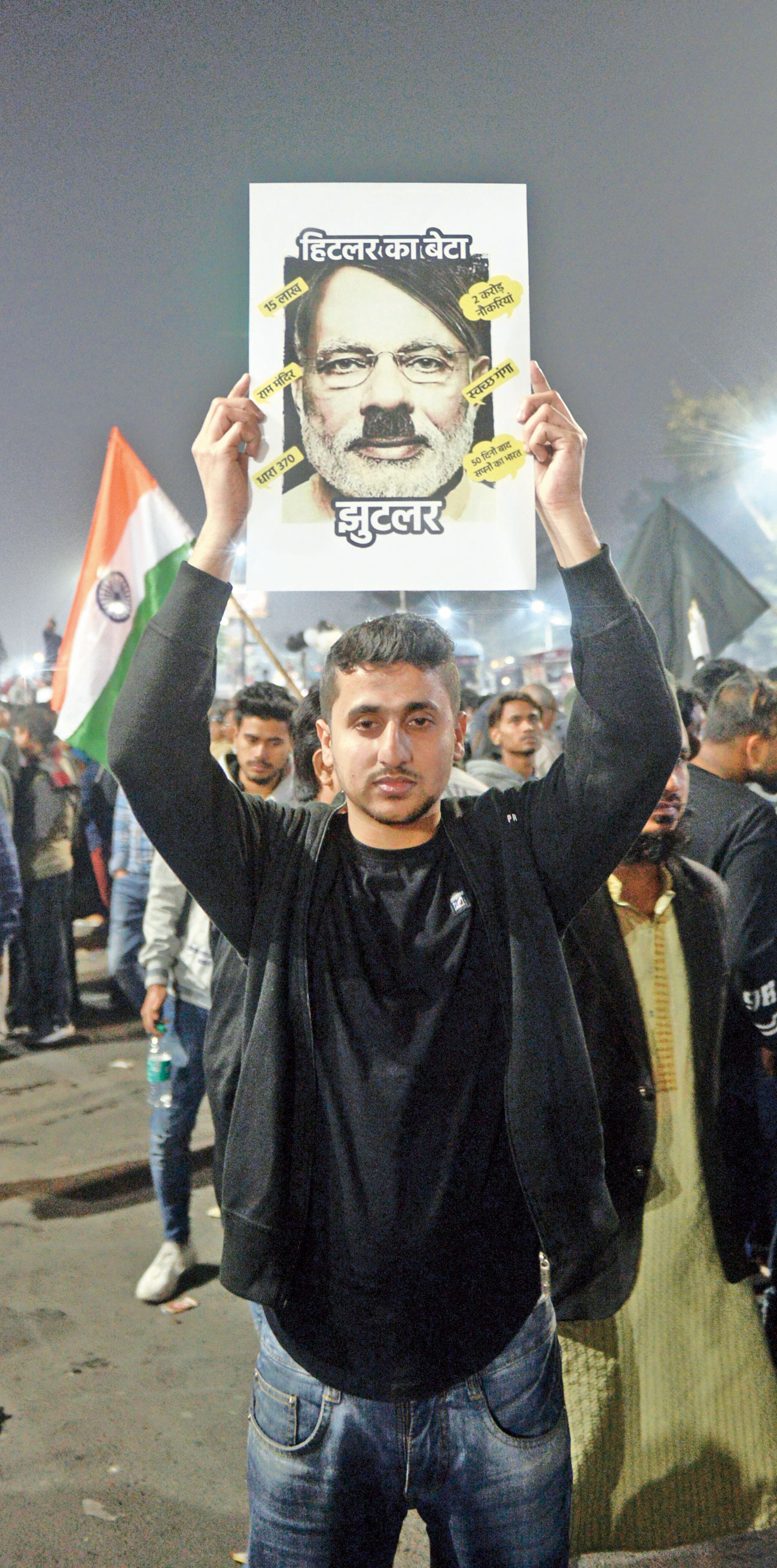 A protester holds a poster that read “Hitler’s son Jhootler”