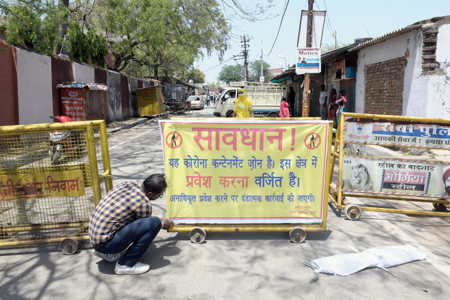 A district administration employee sticks a poster at Hindpiri in Ranchi on Saturday that bars people from the hotspot. 