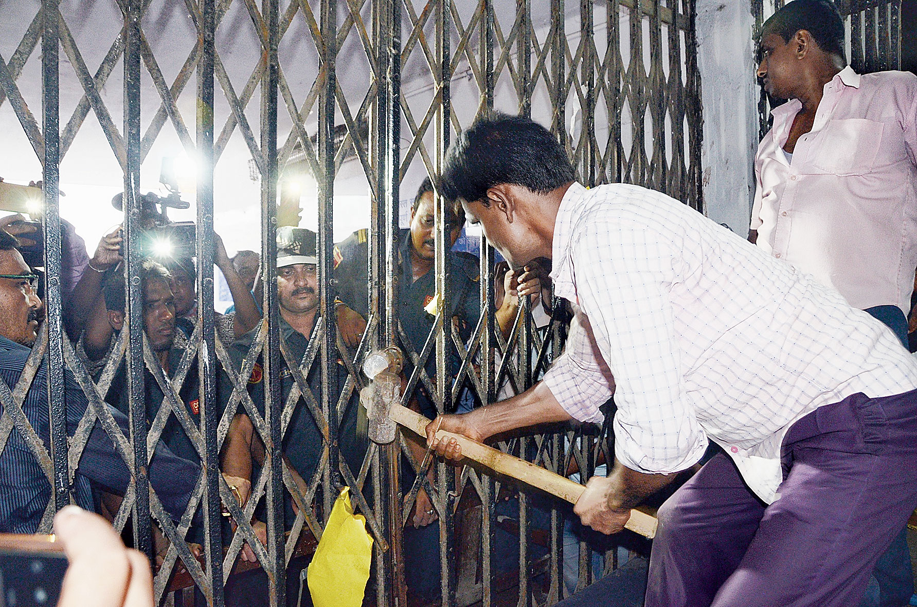 An employee smashes with a sledgehammer the lock on the emergency ward gate at Burdwan Medical College and Hospital on Wednesday. 