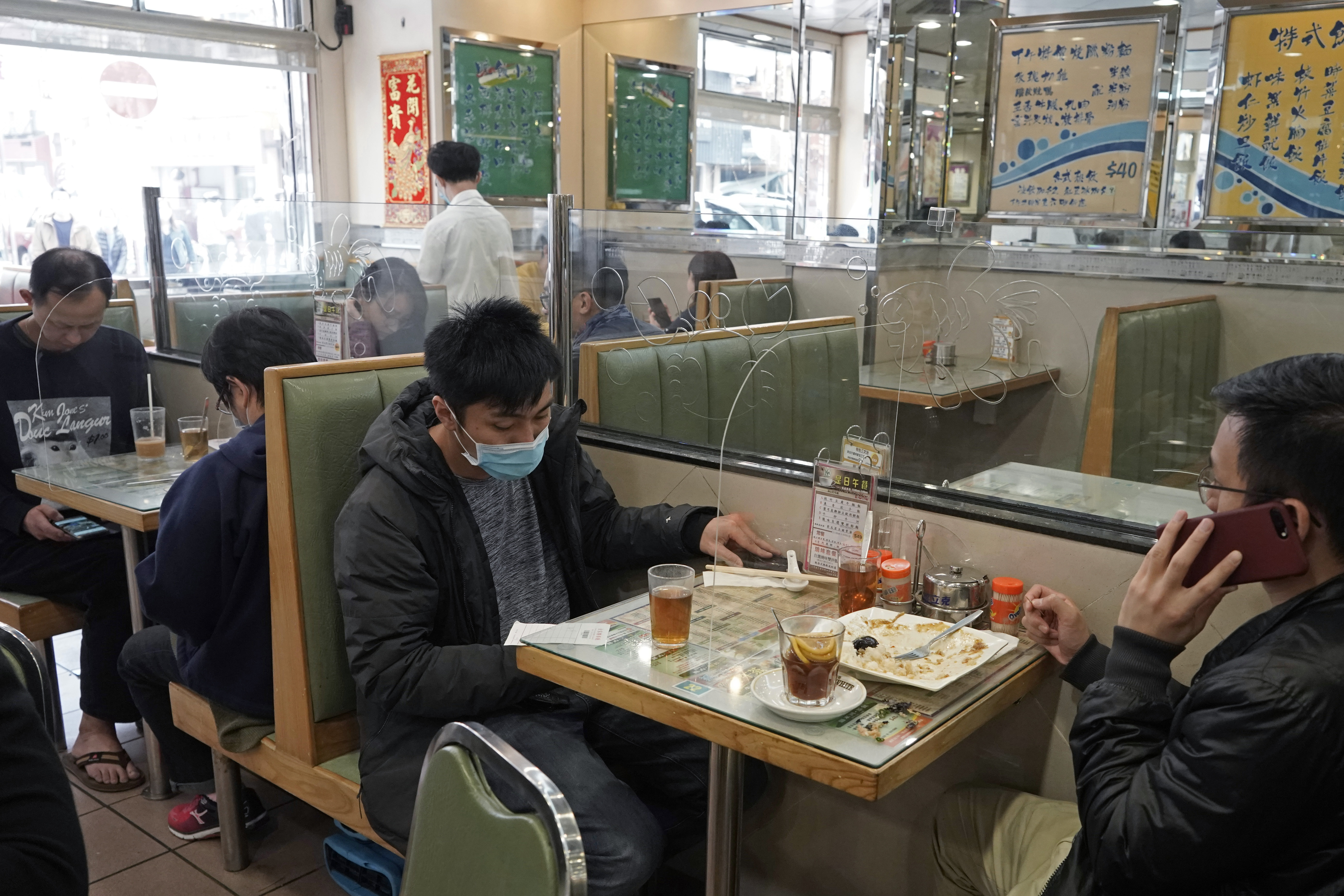 Customers have lunch with a transparent plastic panel between them to help prevent the coronavirus from spreading in Hong Kong