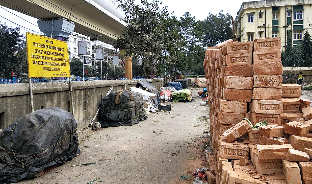 A signage announces the housing project as construction material are piled up on the same stretch.