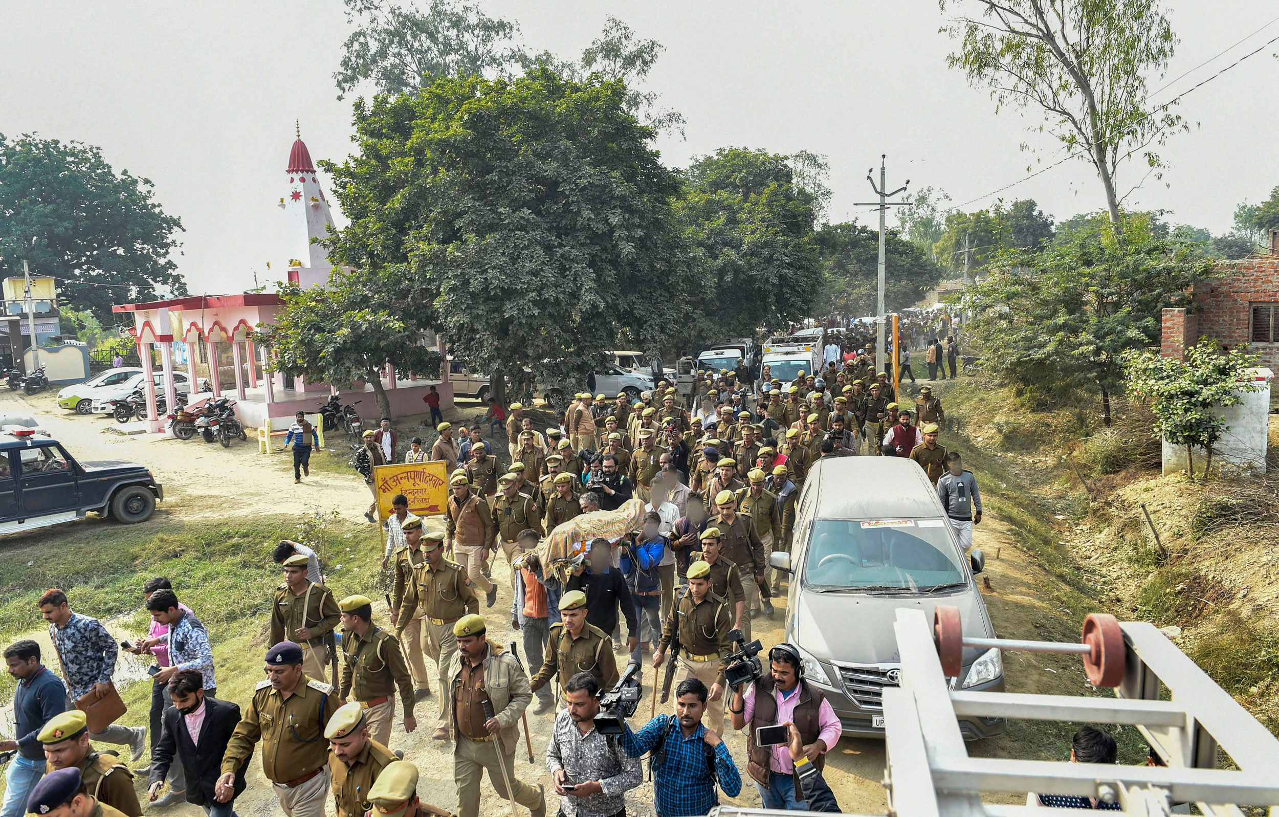 Police officers march as family members and relatives carry the mortal remains of the rape victim for burial at Unnao on Sunday. 