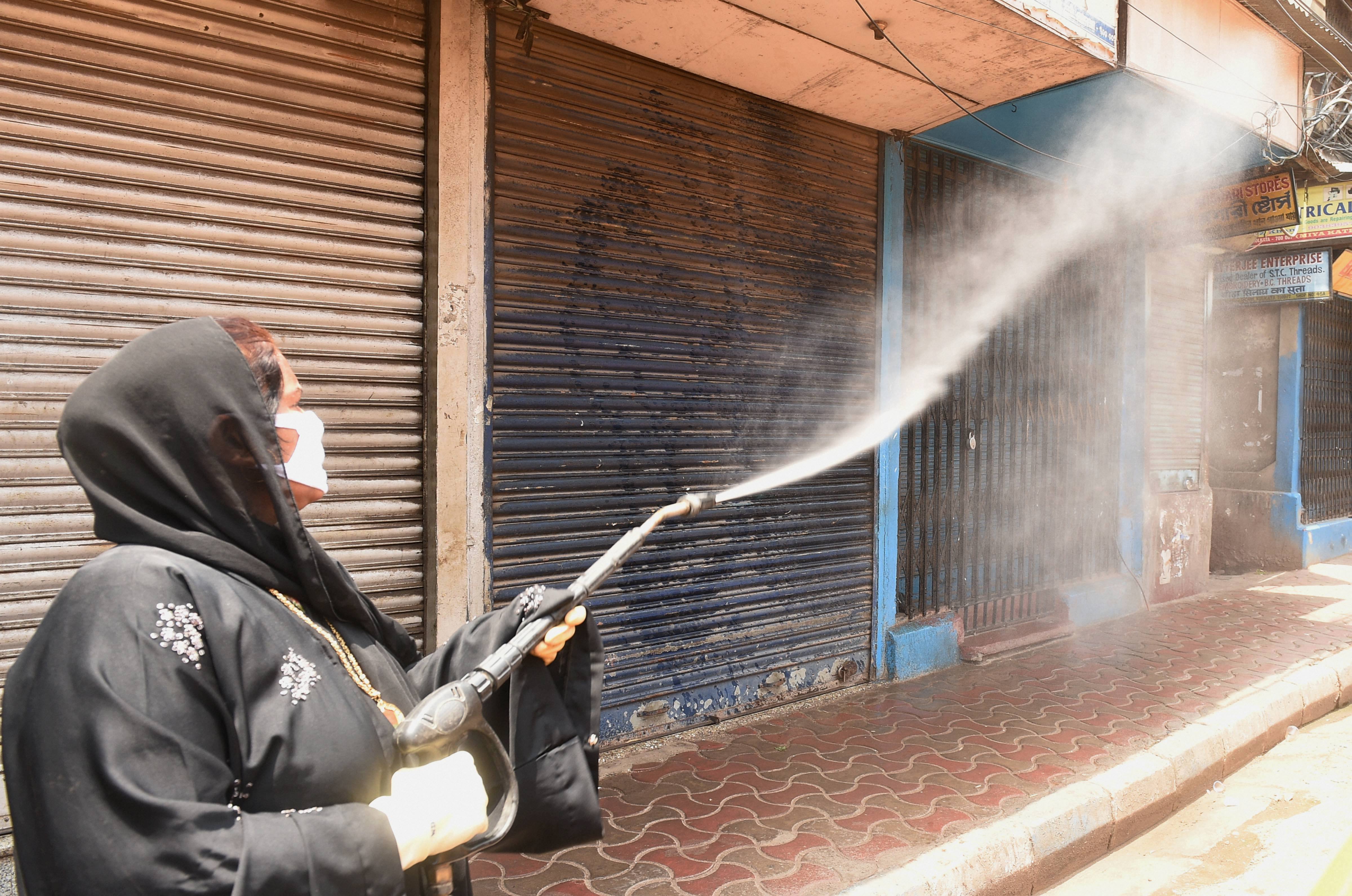 A worker sprays disinfectant on closed shops during the ongoing nationwide lockdown in the wake of coronavirus pandemic, in Calcutta, Saturday, April 25, 2020.