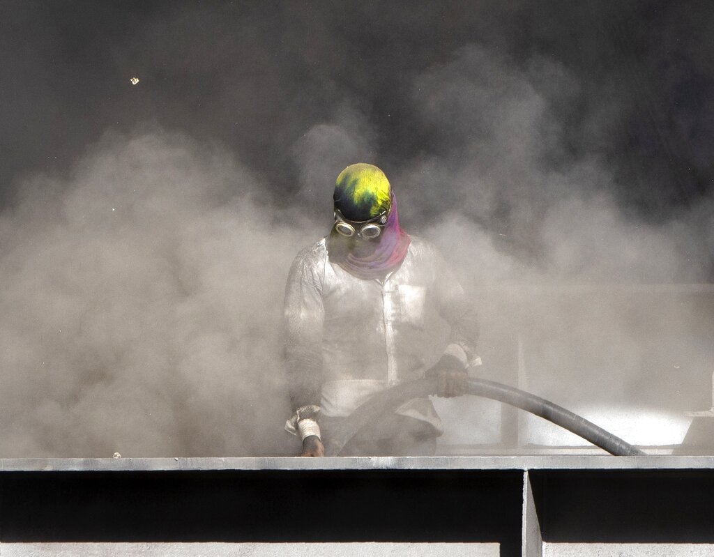 A worker cleans a foot bridge construction site at a train station in Mumbai, Monday, May 4, 2020.