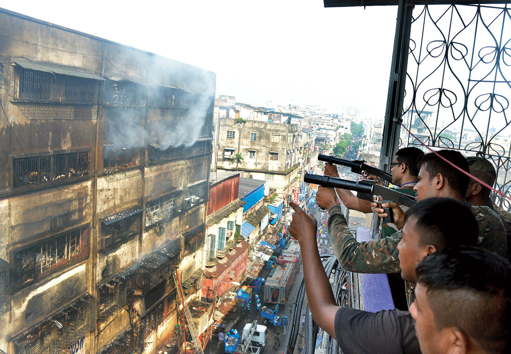 Rubber bullets being fired to break glass panes and let the smoke out of the top floors of Bagree Market on Wednesday. The flames were doused in the afternoon. 