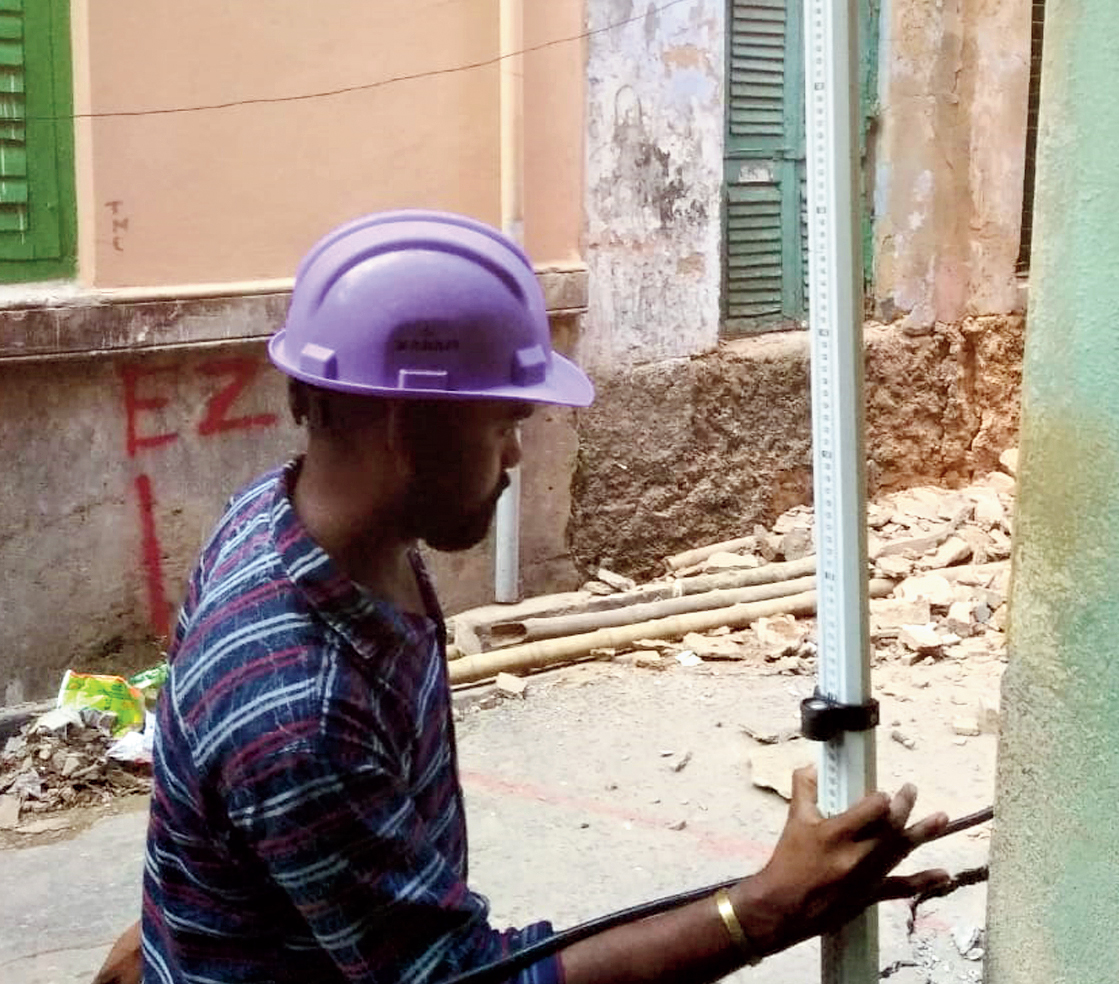 An engineer places a scale to measure subsidence suffered by the building.