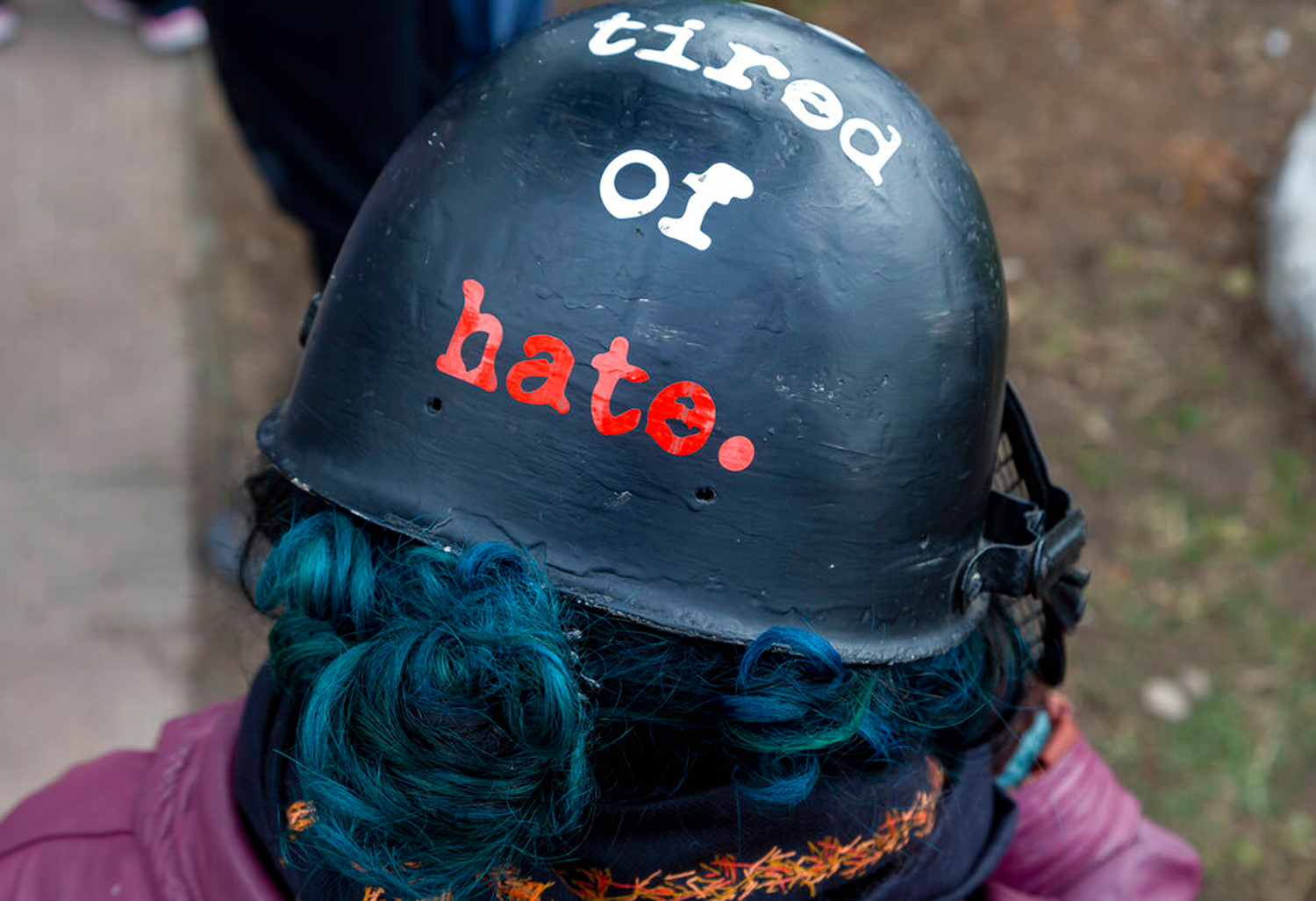 A woman wears a helmet with the words 'The World is Tired of Hate' as she participates in a gathering protesting the Citizenship Amendment Act and the National Register of Citizens in Dharmsala.