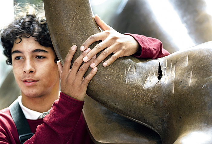 A boy hugs the damaged horn of the Charging Bull sculpture in New York