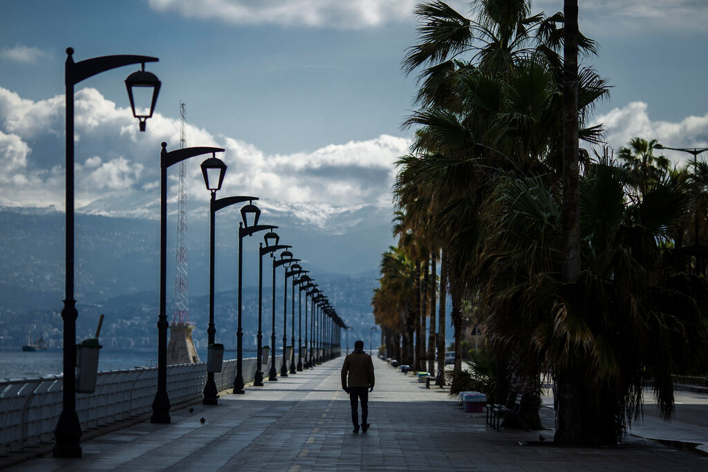 A man walks at Beirut's seaside corniche, or waterfront promenade, along the Mediterranean Sea, which is almost empty of residents and tourists in Beirut, Lebanon, Saturday, March 21, 2020.