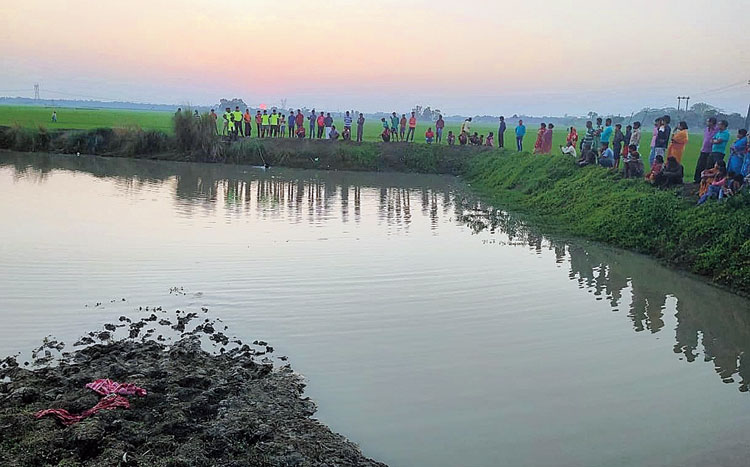 Villagers on Monday gather near the pond in which the four children drowned.