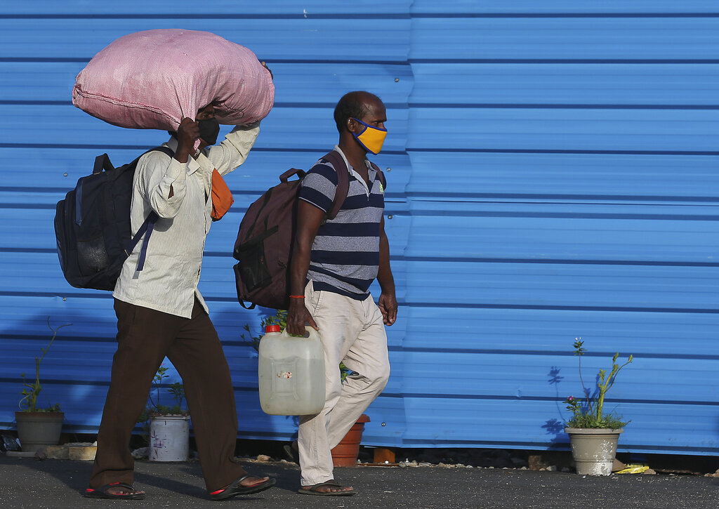 People wearing face masks carry their luggage and walk to board trains to return to their home states in Hyderabad, Saturday, June 13, 2020