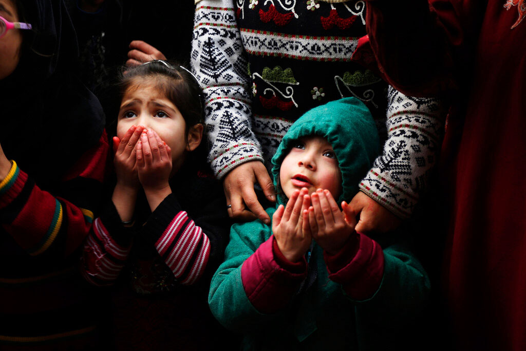Children pray as a priest displays a relic of Sufi saint Sheikh Syed Abdul Qadir Jeelani outside his shrine in Srinagar on Monday. Devotees gathered at the shrine for the 11-day festival that marks the death anniversary of the Sufi saint.