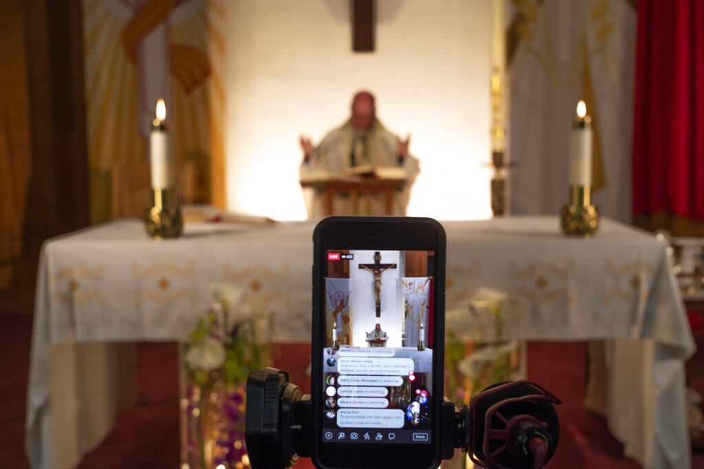Pastor Nicolas Sanchez is seen on his iPhone used to live-stream in celebration of Easter Vigil Mass at St. Patrick Church in North Hollywood, Calif., on Saturday, April 11, 2020. 