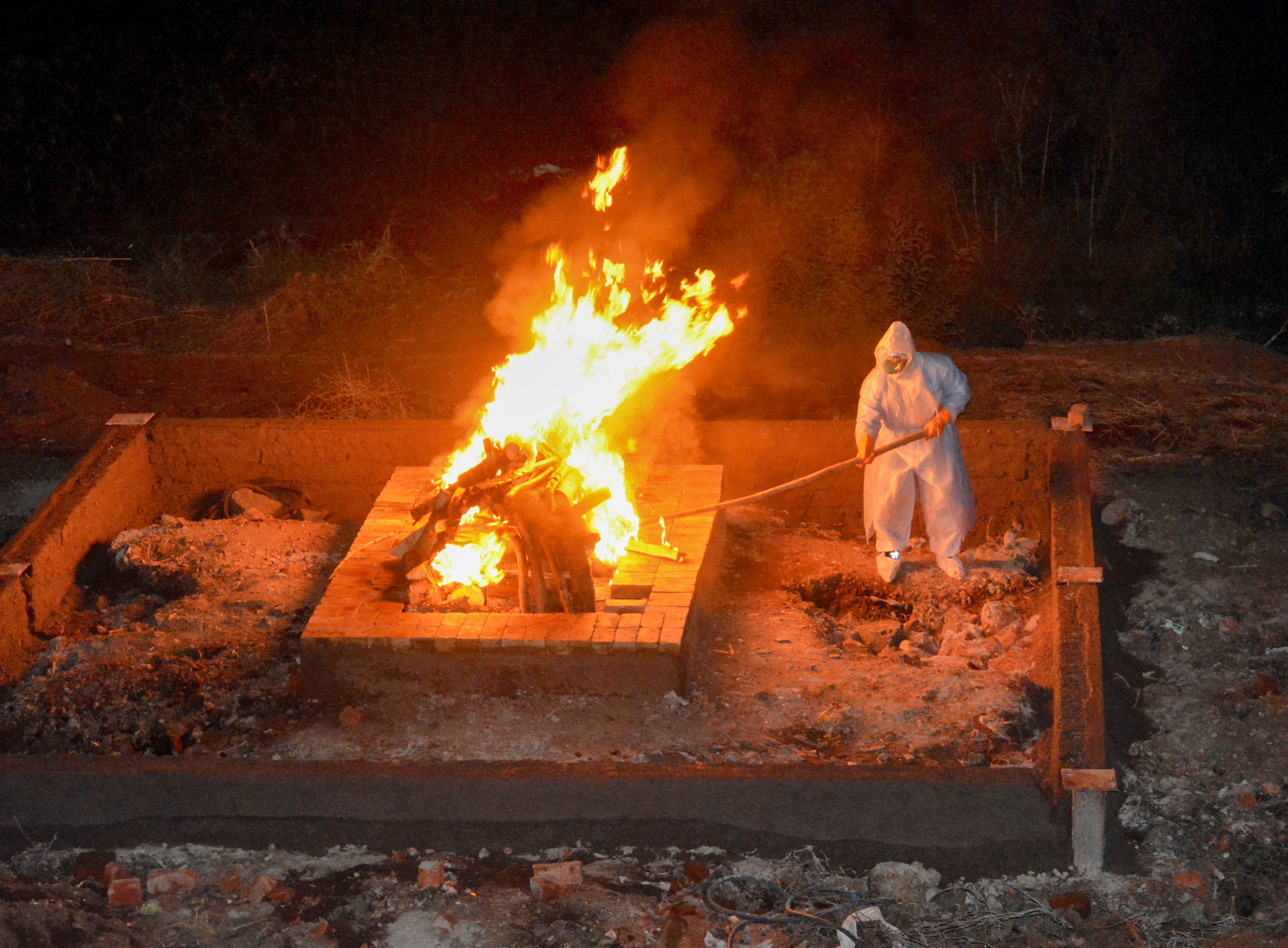 A municipal corporation worker wearing protective outfit cremates the mortal remains of a Covid-19 patient