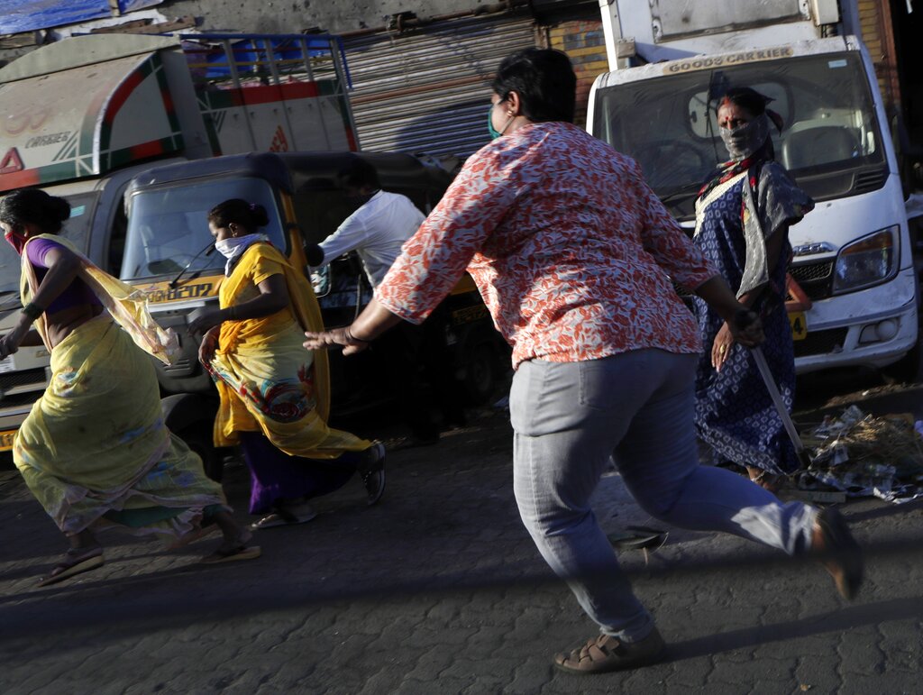 A police officer in plain clothes baton-charges a group of women who had gathered anticipating aid after they refused to disperse despite requests from police, during the lockdown at the Dharavi slum, a Covid-19 hotspot in Mumbai, Wednesday, May 6, 2020.