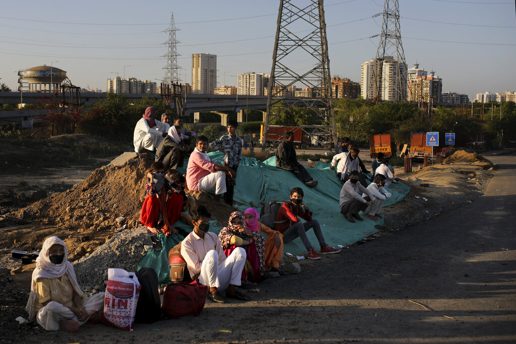 A group of migrant workers rest as they wait for transportation to their village following a lockdown amid concern over spread of coronavirus in New Delhi, on Saturday, March 28, 2020.