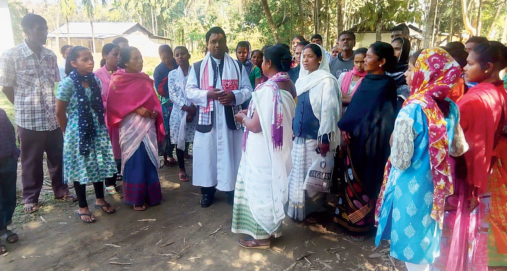 A priest interacts with the family members of the hooch victims in Golaghat on Saturday. 