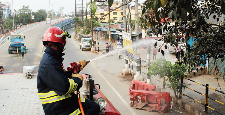 A fire and emergency services worker sanitises GMCH Road in Guwahati on Wednesday. 
