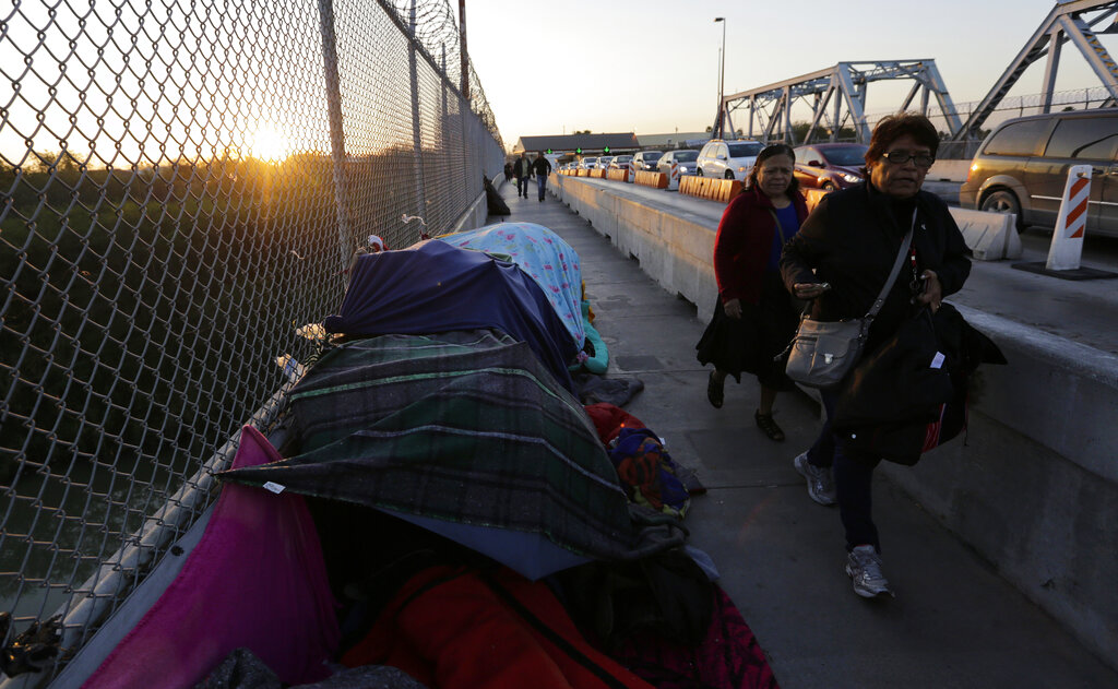 Pedestrians pass a makeshift encampment where migrants seeking asylum wait in Matamoros, Mexico, on a bridge connecting the US and Mexico. Trump administration officials argue many asylum seekers are making illegitimate claims to enter the US for years while their cases are processed. Immigration courts last year denied asylum in about 65 per cent of cases.
