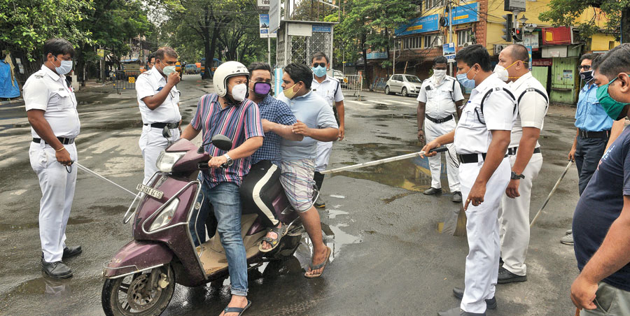 lockdown check: Police stop a scooter with three men, two of whom were not wearing helmets, on CIT Road during the lockdown around noon on Wednesday. When asked why they were out, the three said they were going to a hospital. Cops let two of them go, the third was made to return home.