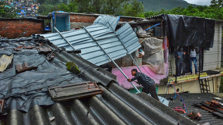 A man repairs the roof of his house damaged during heavy rains at Indira Nagar area of Thane on Thursday