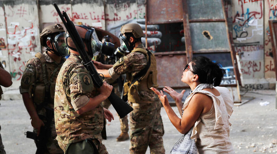 An anti-government protester, reacts in front of Lebanese soldiers during a protest against the political elites and the government, in Beirut, Lebanon, Saturday, August 8, 2020.