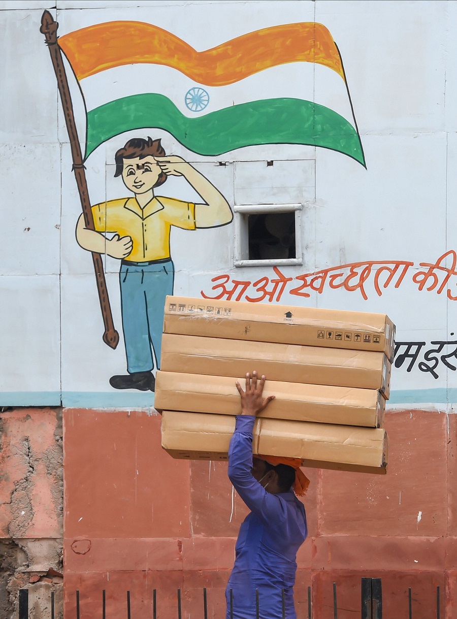 A porter walks past a wall with a Tri-colour painted on it as part of a cleanliness campaign, in New Delhi.
