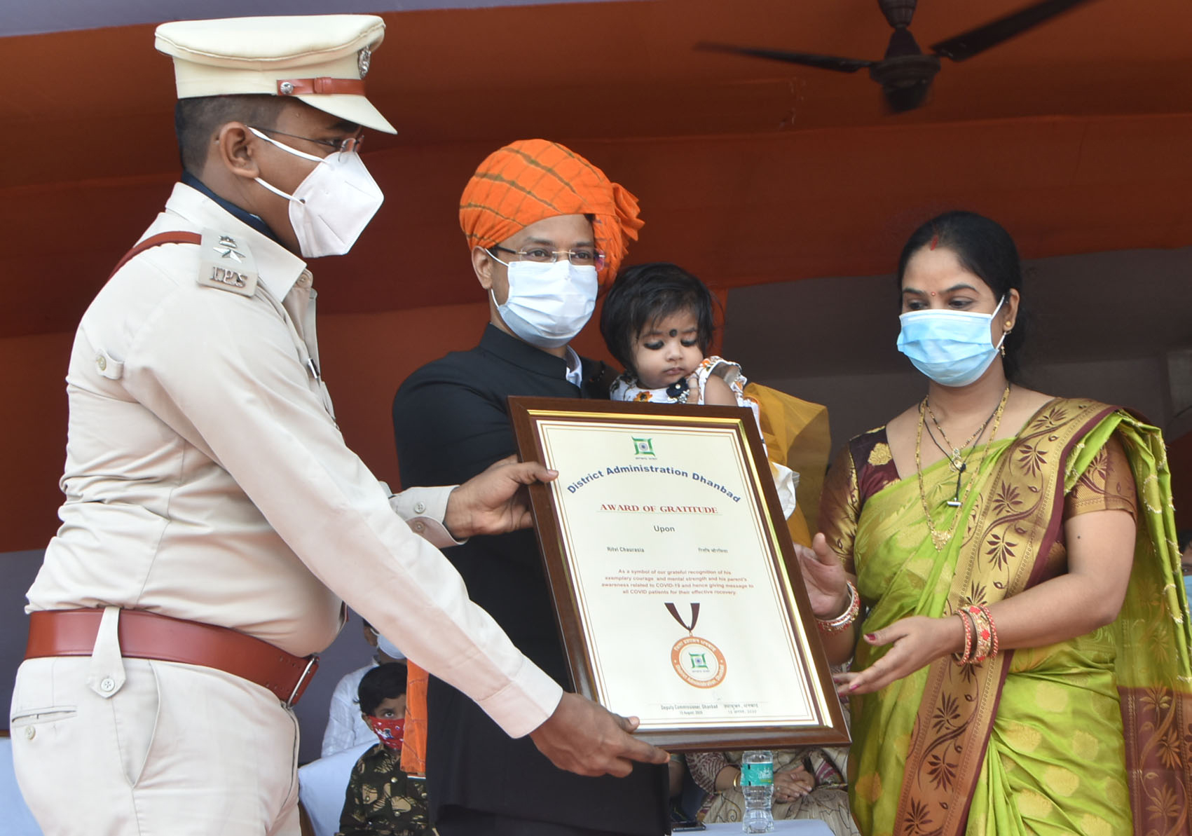 Dhanbad DC Uma Shankar Singh holding the youngest person who defeated the coronavirus, Ritwi Chaurasia (four months old), and felicitating her mother