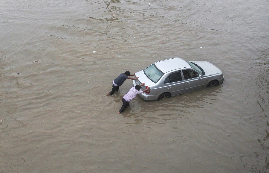 Men push a car stuck at waterlogged Hero Honda Chowk near Delhi-Gurgaon Expressway after heavy rain on Wednesday