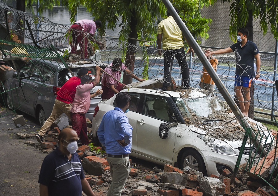 Workers remove the debris after wall of a public school collapsed due to heavy rains in New Delhi on Wednesday