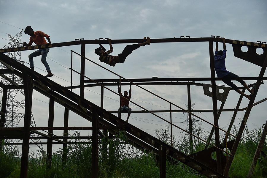 Boys play on a structure as the weather cools following heavy monsoon rain, in New Delhi on Wednesday
