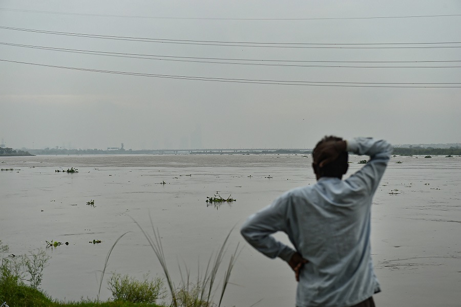 A man stands at the bank of Yamuna River as its water level rises after heavy monsoon rain in New Delhi on Wednesday