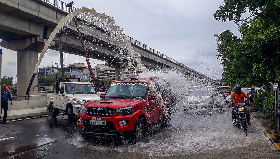 Rain water comes out from a motor pump as firefighters clear the waterlogged Golf Course Road underpass after heavy rains, in Gurugram on Thursday.