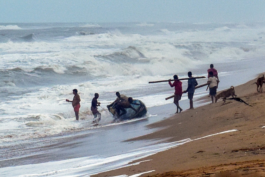 Fishermen pull their boat ashore during rain, in Puri on Wednesday