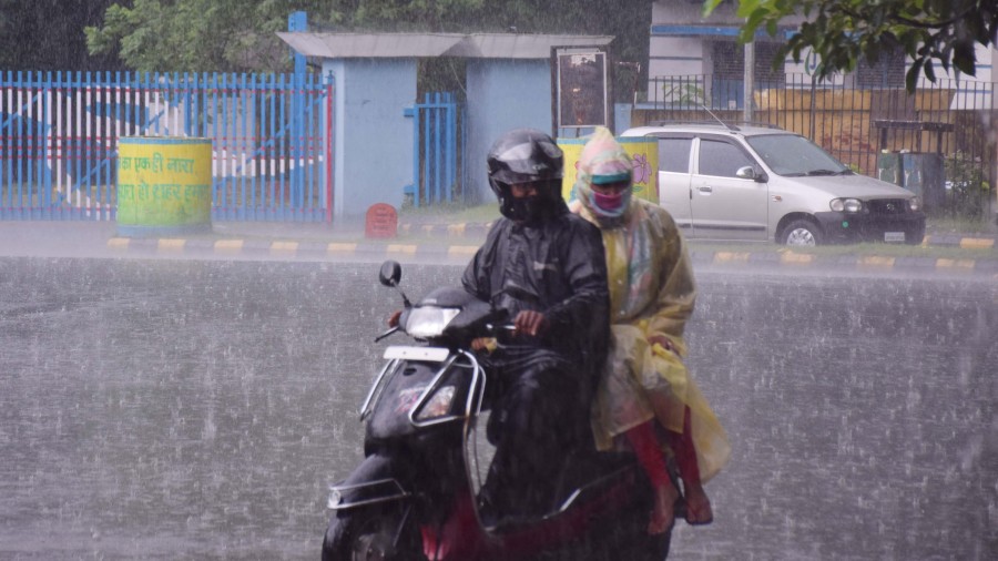 People travelling on a motorcycle amid in heavy rainfall at Sakchi in Jamshedpur on Friday. 