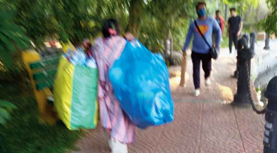 A woman carries bags full of plastic bottles that she picked up from inside Rabindra Sarobar. Daily visitors said she was helping keep  the place clean of plastic left behind