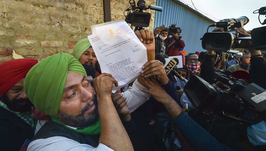 A representative of a farmers' union at the SInghu border holds up a copy of the government's draft proposal sent to them on Wednesday.