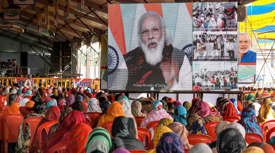 Farmers watch the live telecast of Prime Minister Narendra Modis speech on a screen during Kisan Mahasammelan, in Raisen on Friday, Dec. 18, 2020. 