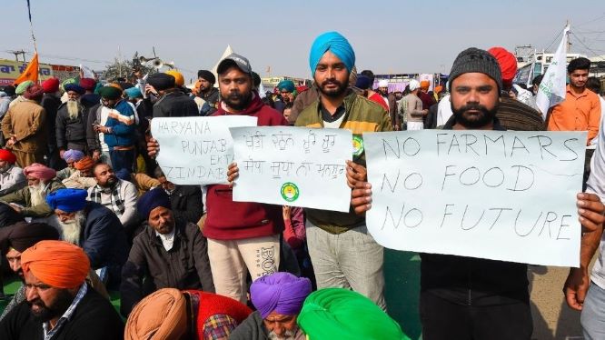 Farmers display placards during their sit-in protests against the three central farm laws at the Singhu border near Delhi, on Sunday.