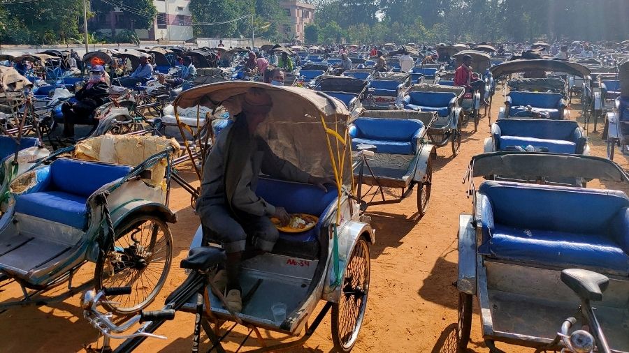 Amid a sea of rickshaws, a puller has his lunch at the Loyola Ground, provided by church authorities in Ranchi, on Friday.