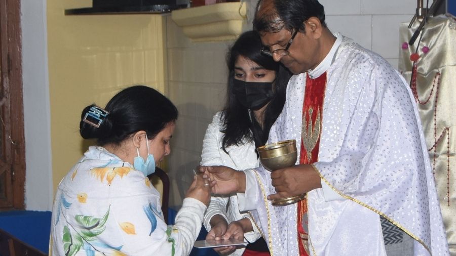 Fr. Prakash Topno serves Holy Communion to a devotee during Christmas rituals, at St. Anthony's Church on Friday, in Dhanbad.