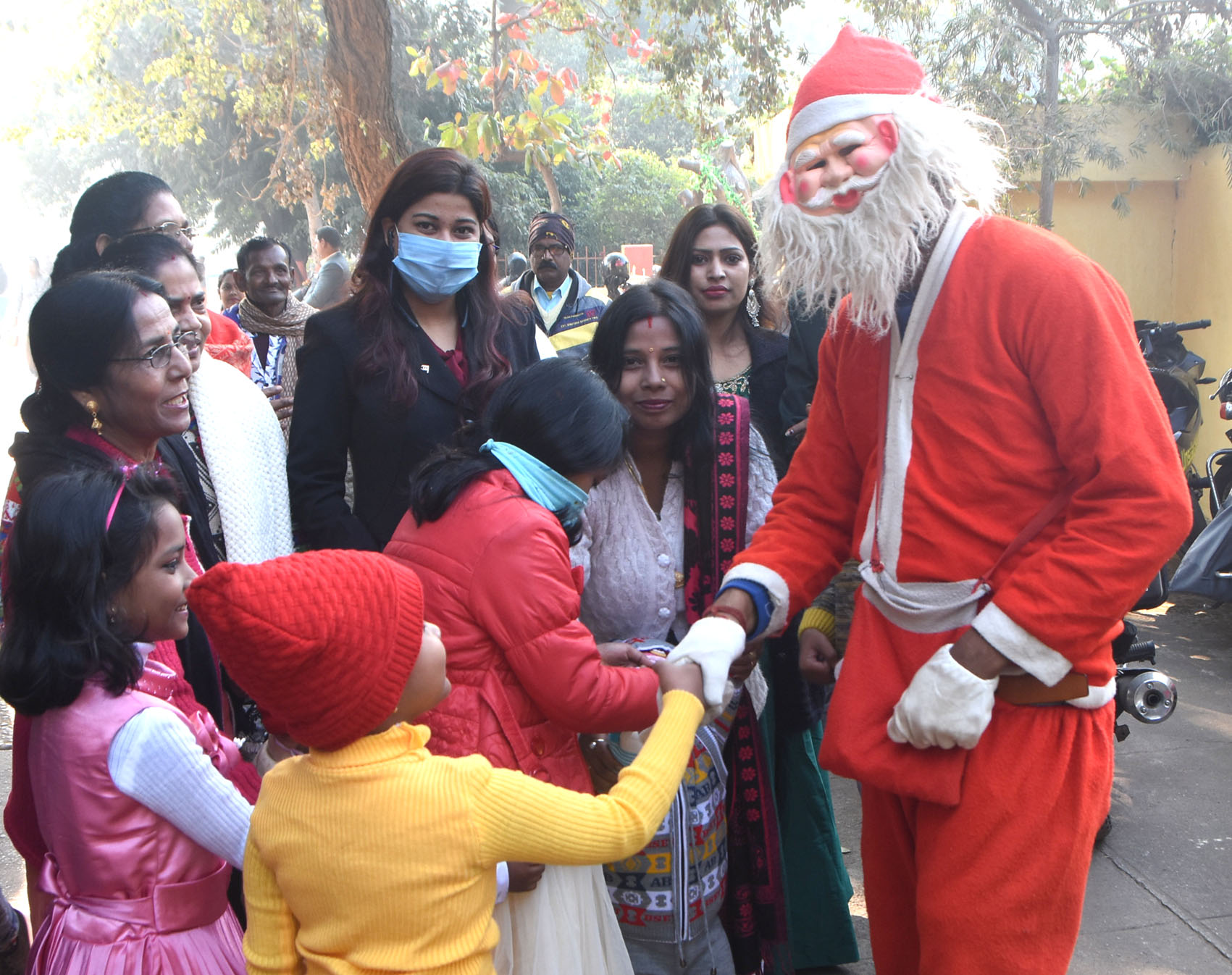 Man dressed up as Santa Claus distributes chocolates among children and shakes hand with them at St. Anthony’s Church in Dhanbad, on Friday.