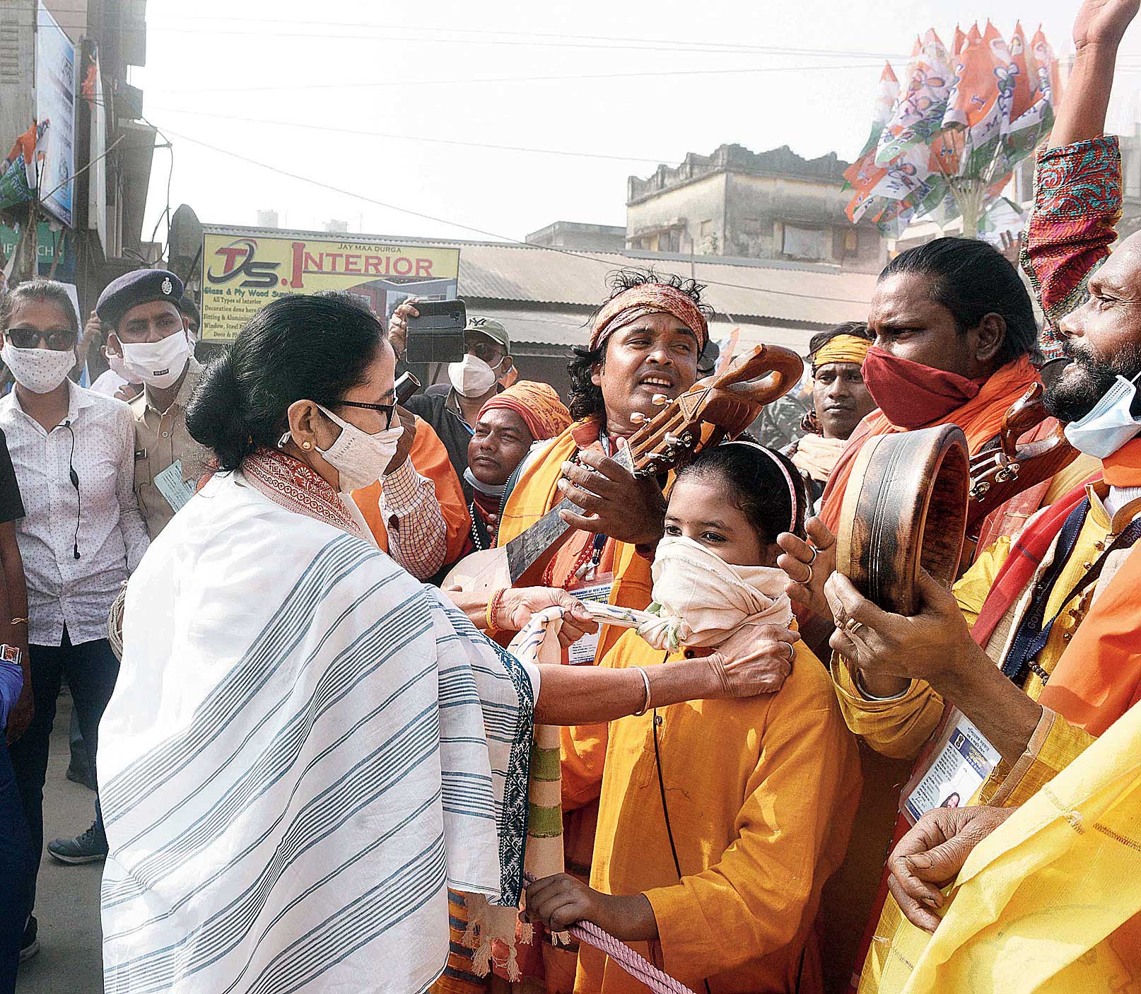 Mamata helps a child tie a handkerchief as a mask.