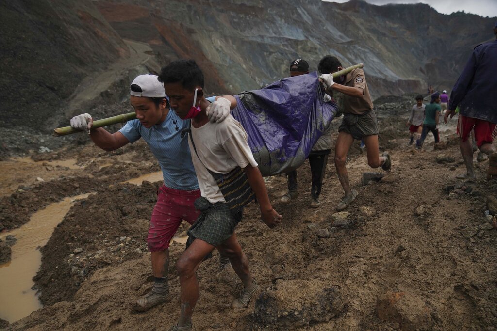 Rescue workers use poles to carry a body shrouded in blue and red plastic sheet on Thursday in Myanmar