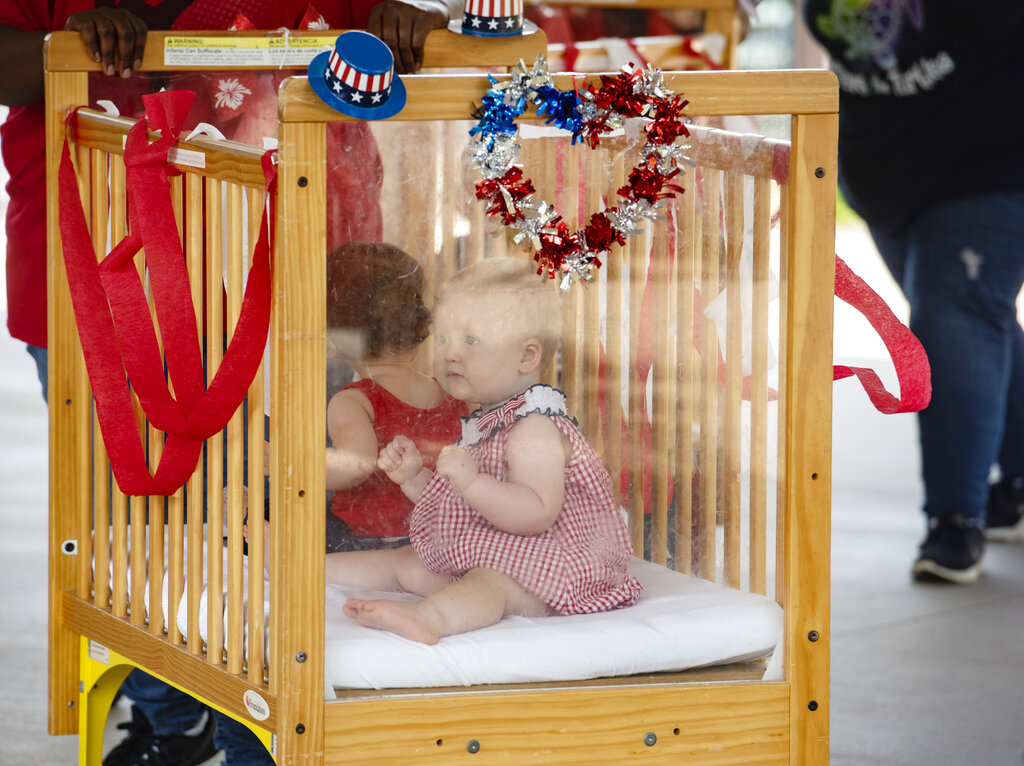 A baby from Stepping Stone School in Tyler, Texas, rides in a crib for their annual parking lot Fourth of July parade on Friday, July 3, 2020. Guests attending the event, including parents, wore face masks and viewed the parade from a distance due to the coronavirus pandemic. Stepping Stone caters to early education and preschool. 