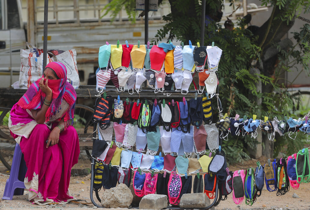 A woman waits for customers for face masks on a pavement in Hyderabad, India, Friday, July 3, 2020.