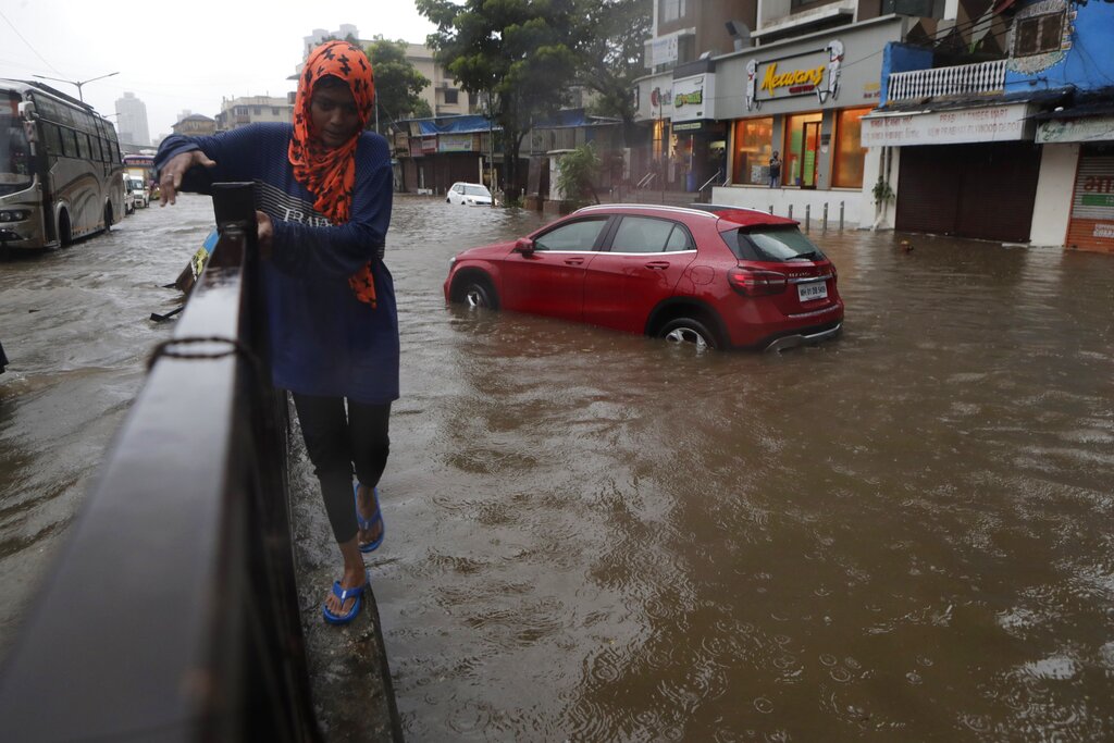 A woman walks past a waterlogged street after heavy rainfall in Mumbai, Saturday, July 4, 2020.