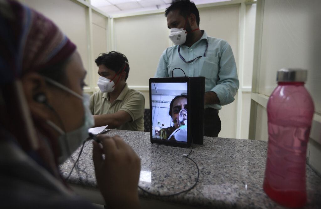 A woman talks to her mother who is admitted in a Covid-19 hospital through a video phone facility by the help desk outside a hospital, in New Delhi, India, Friday, July 3, 2020.