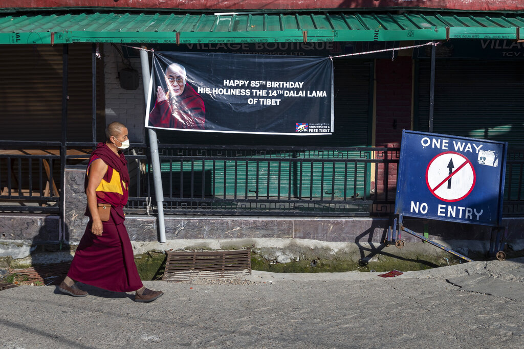 An exile Tibetan Buddhist monk walks past a banner wishing Tibetan spiritual leader the Dalai Lama on his 85th birthday in Dharmsala, India, Monday, July 6, 2020. 