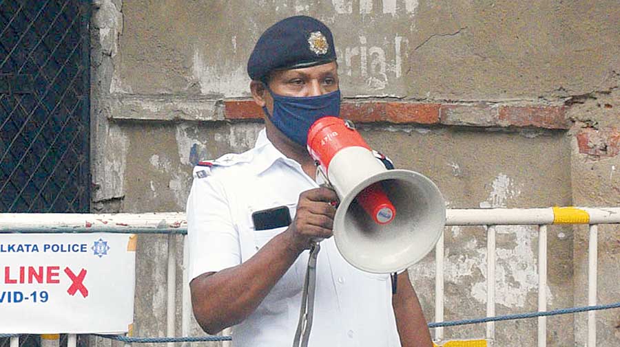 A policeman makes announcements on a loudhailer, asking residents to stay indoors and follow lockdown rules, in Bhowanipore on Wednesday